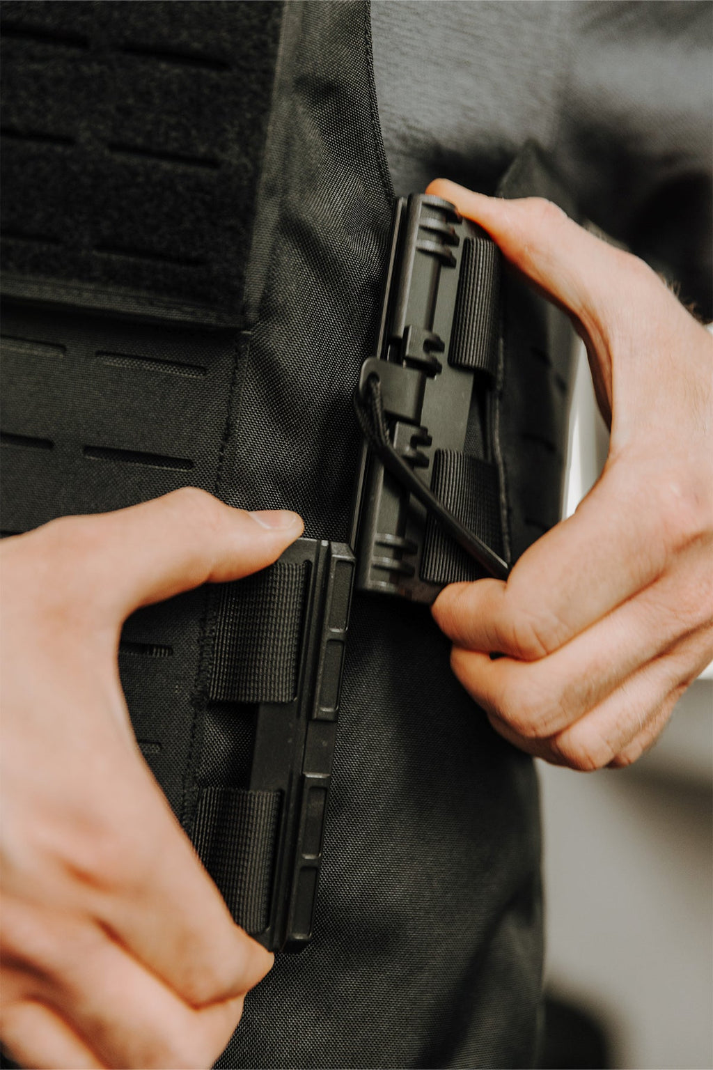 Detailansicht: Schwarze Weste mit Magazinhalterung, Hände platzieren ein Magazin