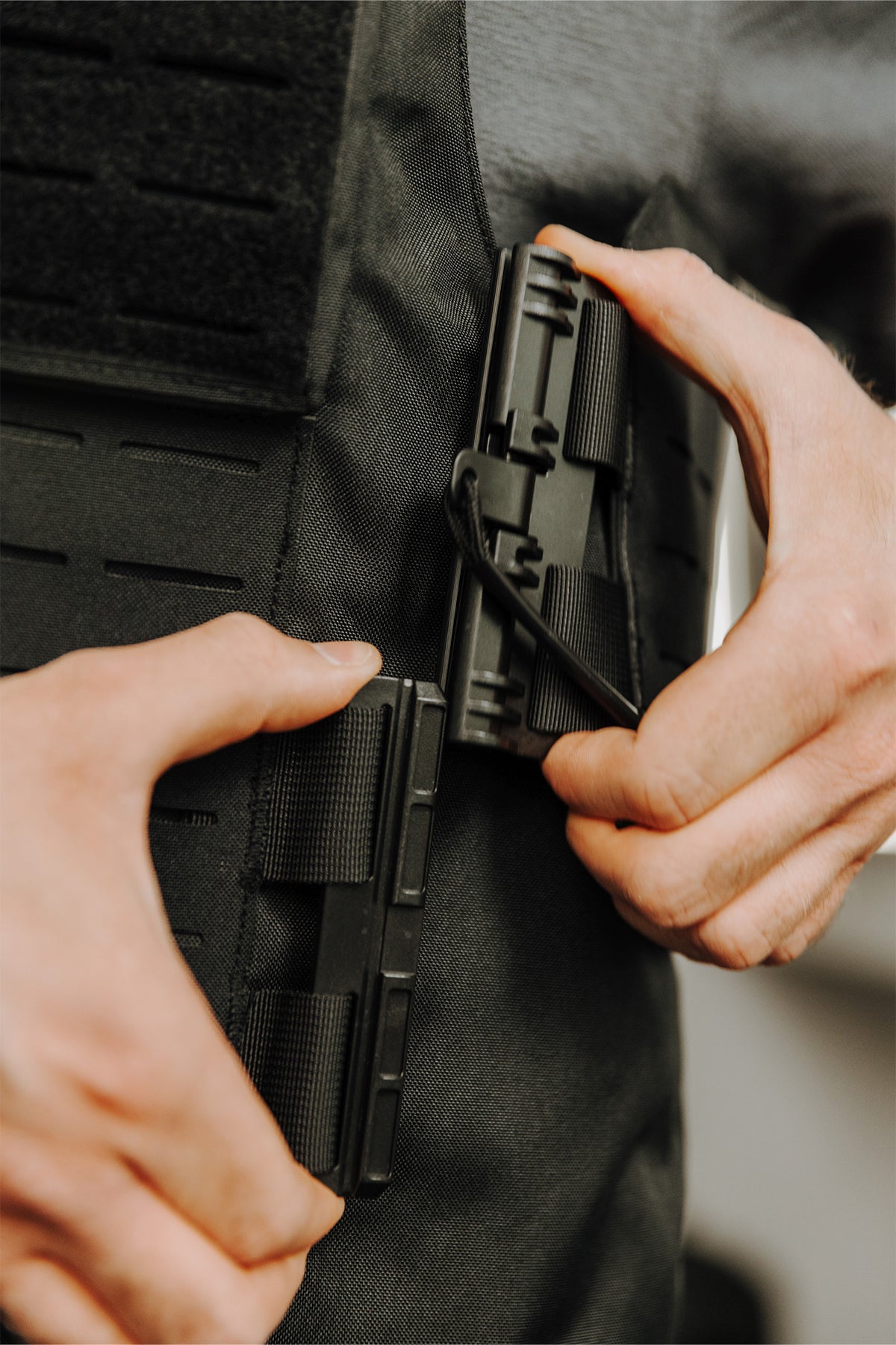 Detailansicht: Schwarze Weste mit Magazinhalterung, Hände platzieren ein Magazin