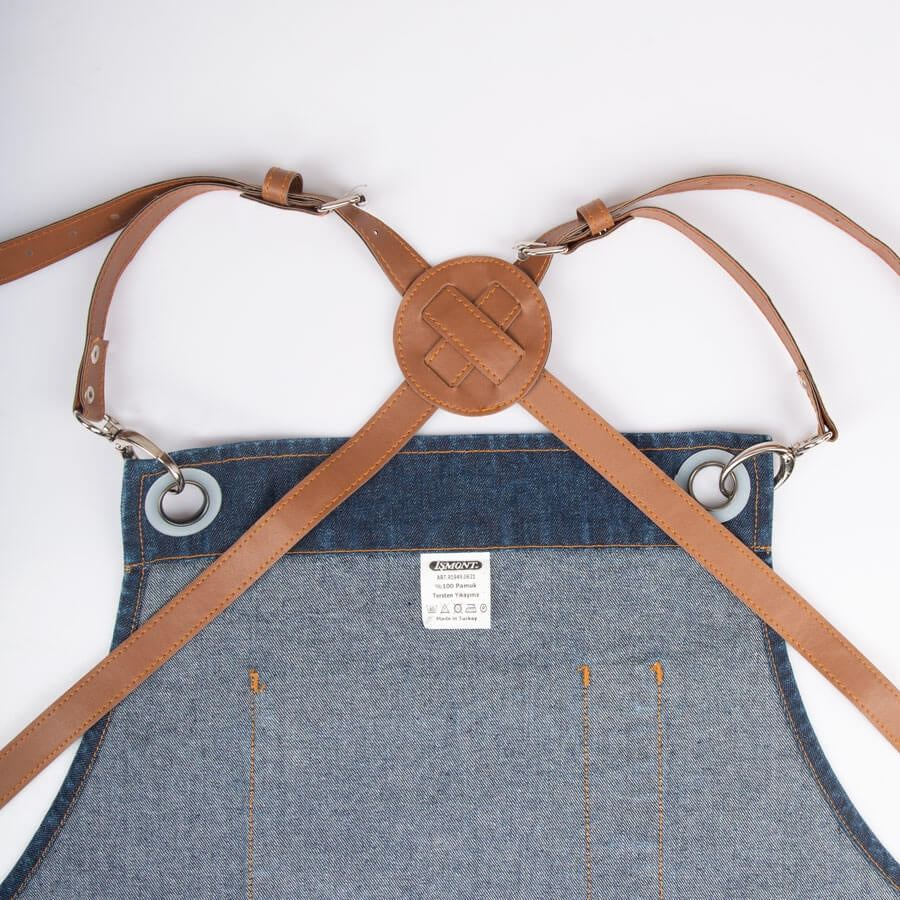 Marineblaue Schürze aus Jeansstoff mit Querträgern, Metallringen und Brustlabel