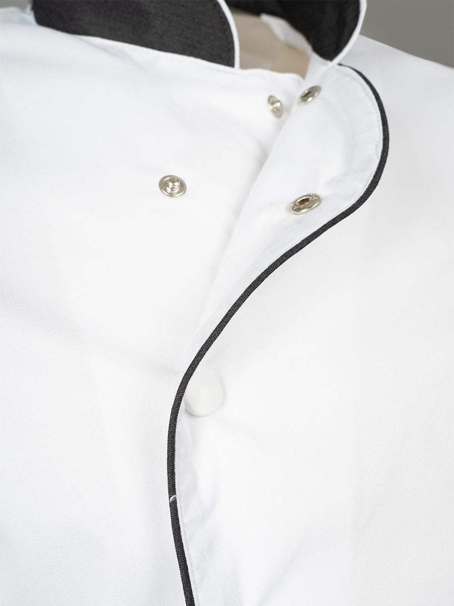 Detail: weiße Kochjacke mit schwarzer Einfassung und Metallknöpfen am Kragen