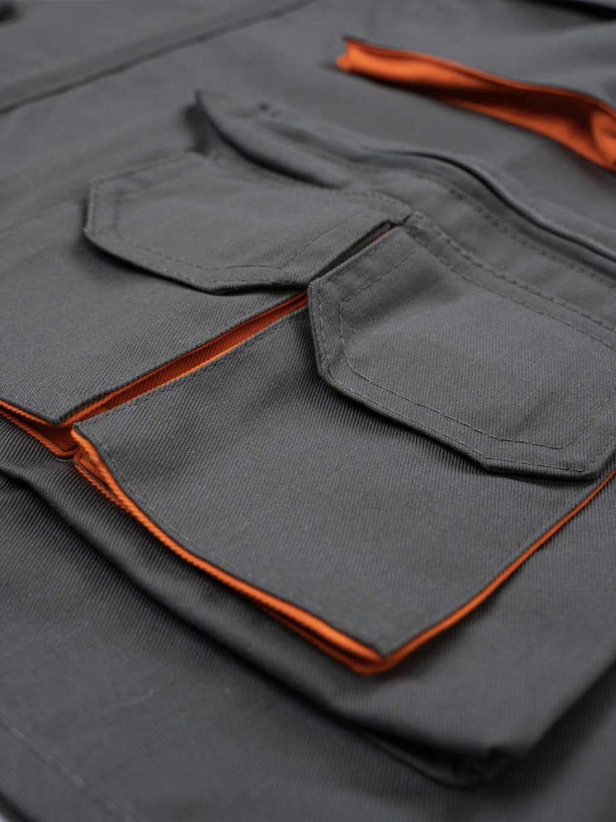 Arbeitsweste Detail: grau, Taschenklappe mit orange eingefasster Kante und Ziernähten