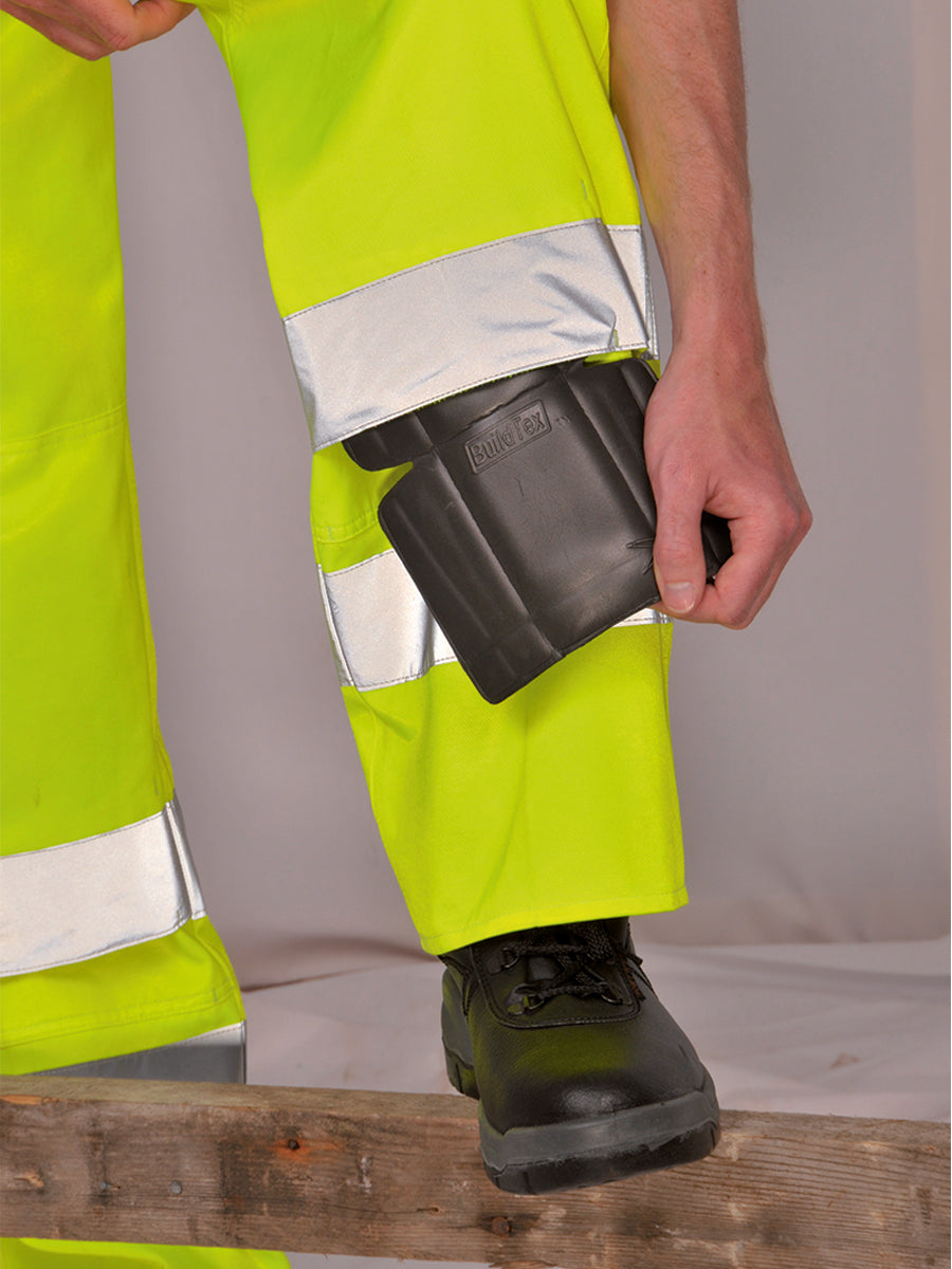 Portwest Warnschutzhose gelb mit Beintasche, Person steckt Handwerkzeug ein