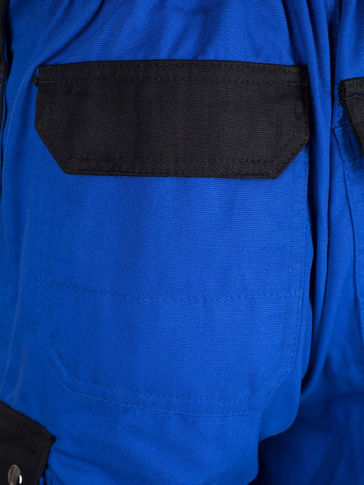Brusttasche der Arbeitslatzhose mit schwarzem Einsatz und sichtbarer Absteppung.